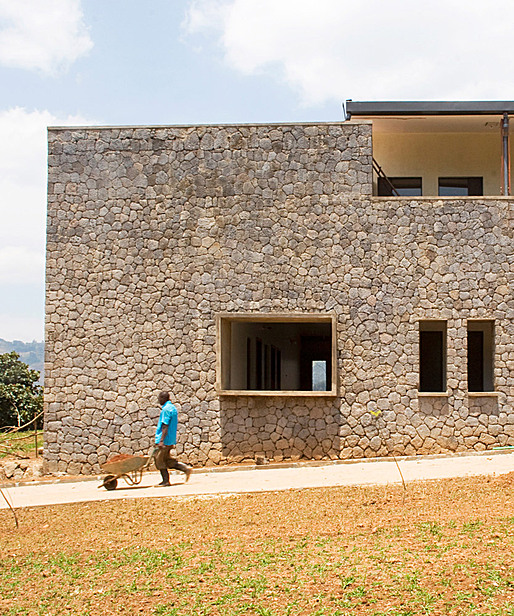 Worker passes by masonry walls. (Photo courtesy of MASS Design Group)