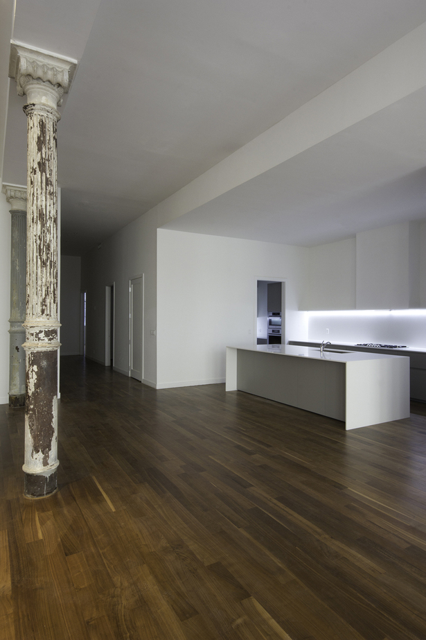 Against the wall, the base cabinets in the same color are dominated by the hood: a sculptural chimney structure that goes all the way to the top of the 15ft ceiling.