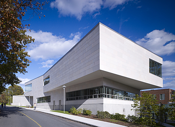 West and south facade showing exterior materials: zinc-coated copper coping, limestone, bush-hammered concrete, and aluminum windows