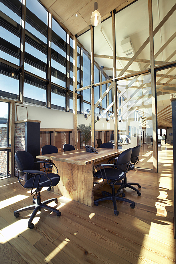 Existing ceiling and floor substrates and framing was removed, milled and reapplied as finished floor materials. New furniture, including this conference room table, was fabricated from old growth framing from the original structure.