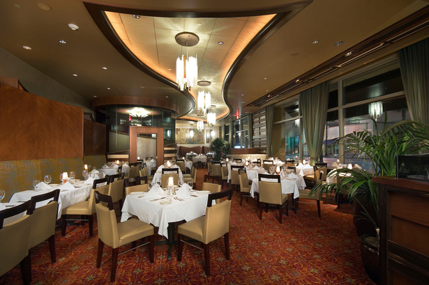 Dining room with custom finishes, original wall art, and a private curved glass wine room.
