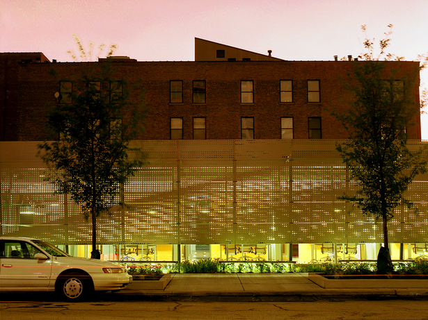 In the evening the appearance of the building is transformed as the taut, opaque scrim allows light to gently pour into the street. (photo by Greg Murphey)