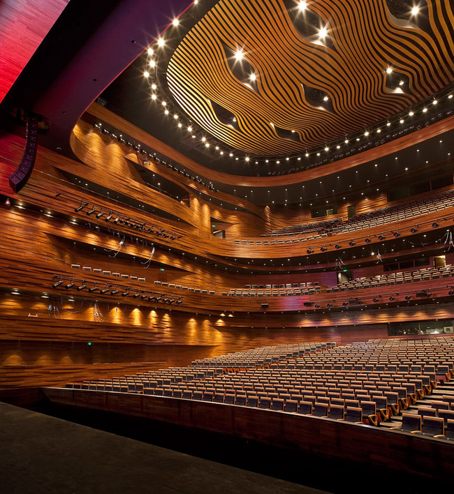 The main auditorium holds 1680 seats. The curved walls are made of 16.000 CNC cut solid bamboo blocks. The golden ceiling reflector design is inspired by the tradition Chinese opera mask. (Photo: Kari Palsila)