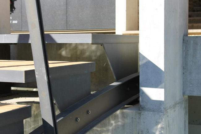 The stairs meet the concrete path, as the reflection of the water dances below