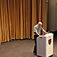 [Gold lamé curtain, with Mark Jarzombek in the foreground.] in Piper Auditorium by Lian